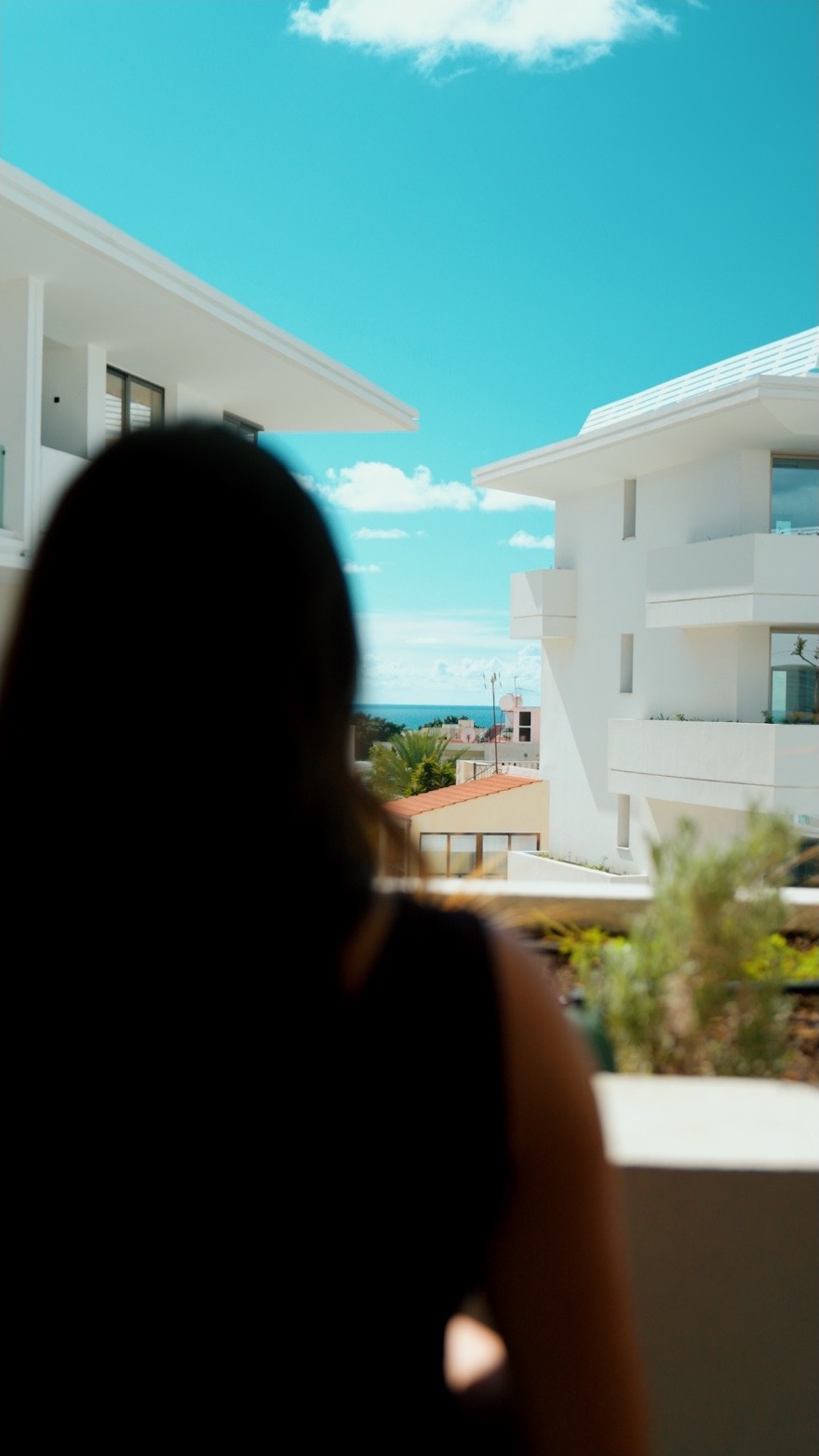 Deborah bei den Dreharbeiten auf Zypern, von hinten mit Blick auf weisse Gebäude und das Meer